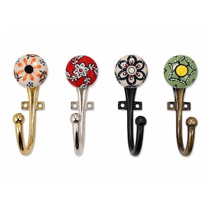 May include: A set of four wall hooks featuring round ceramic knobs with floral patterns. The first hook has a gold finish with an orange and black flower. The second is silver with a red floral design. The third is black with a white and black pattern. The fourth is bronze with a green and yellow flower.