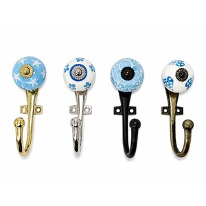 Puede incluir: Cuatro ganchos de pared con pomos de cerámica redondos con patrones azules y blancos. Los ganchos tienen diferentes acabados metálicos, incluyendo oro pulido, plata, negro mate y latón antiguo, con placa de montaje y extremo curvo.