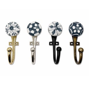 Peut inclure: Quatre patères murales dotées de boutons en céramique ronds avec des motifs floraux ou géométriques bleus et blancs. Chaque crochet présente une finition métallique distincte, dont or poli, argent, noir mat et bronze antique, avec une platine.