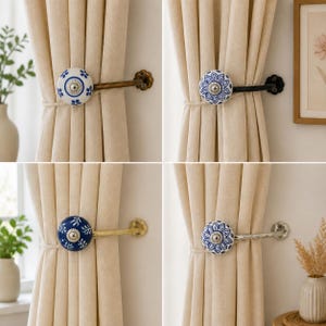 May include: Four curtain tiebacks featuring round ceramic knobs with blue and white floral patterns. Each knob is attached to a metal arm in various finishes including antique brass, black, gold, and silver, mounted to hold beige fabric curtains.