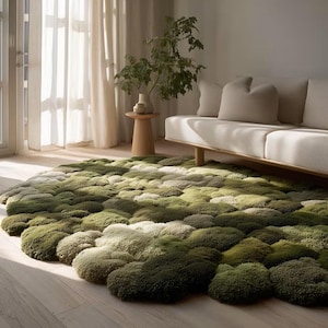 May include: A large, circular area rug featuring a textured, moss-like surface with varying shades of green, ranging from deep forest tones to lighter sage hues. The rug has a soft, tufted appearance with irregular, rounded shapes throughout.