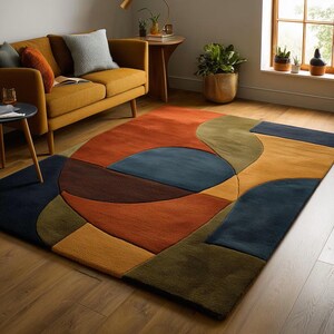 May include: A rectangular area rug featuring a geometric pattern of overlapping shapes in shades of burnt orange, deep navy blue, mustard yellow, and olive green. The design consists of large circles, arcs, and rectangular blocks of solid colour.
