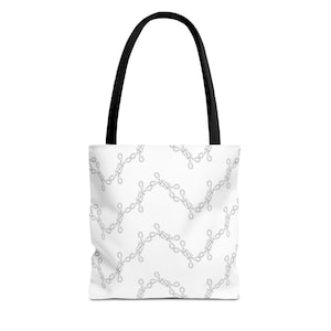 May include: White tote bag with a black handle. The bag features a repeating pattern of gray chain links arranged in a zigzag design. The bag is made of a durable material and is suitable for carrying various items.