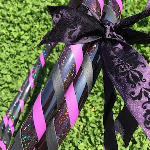 May include: Two black and pink striped hoops with black glitter and a black satin ribbon tied in a bow.