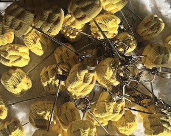 May include: A collection of yellow fire poi heads with metal hardware. The fire poi heads are made of a woven material and are attached to metal rods with adjustable clamps. The poi heads are a bright yellow color.