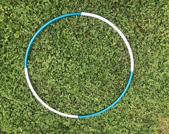 May include: A blue and white hula hoop on a green grassy surface.