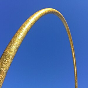 May include: A gold glitter hoop, or hula hoop, against a bright blue sky.