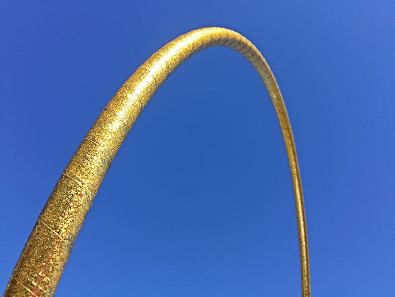 May include: A gold glitter hoop, or hula hoop, against a bright blue sky.