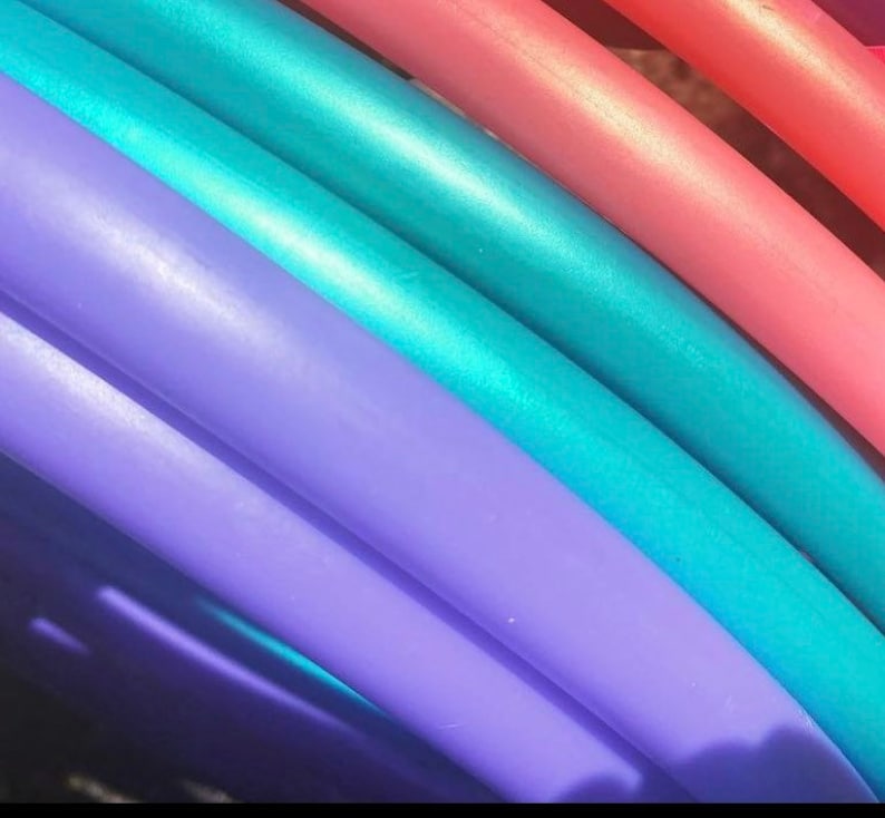 May include: Close-up of a set of colourful plastic hoops, with a teal, purple, and pink hoop stacked on top of each other.