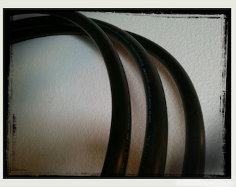 May include: Three black electrical cables bundled together, against a white background.