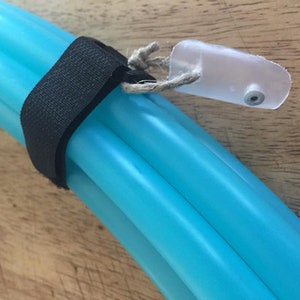 May include: A turquoise plastic hoop with a black strap and a clear plastic connector. The connector has a small hole in it.
