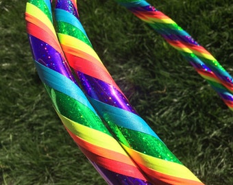 May include: Two rainbow-colored hula hoops with glitter and iridescent tape. The hoops are layered on top of each other, with the rainbow colors facing outward.