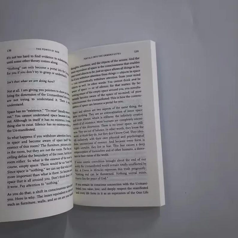 May include: Open book with text on white pages. The text discusses concepts of space, silence, and the Unmanifested. The book is open to pages 138 and 139, with the title "The Power of Now" visible.