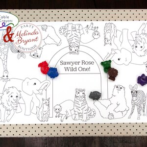 May include: White paper table runner featuring a black and white animal outline design, including a lion, giraffe, and zebra. The text "Sawyer Rose Wild One!" is in the center. Includes colorful crayons.