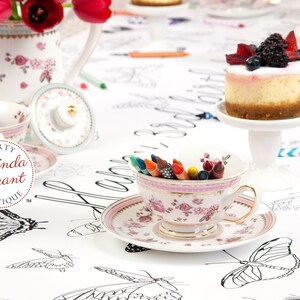 Berry covered mini cheesecakes and tiny cake stands, pretty teacups and saucers filled with crayons, and a china teapot filled with tulips are a fun way to stage this personalized butterfly coloring table runner.