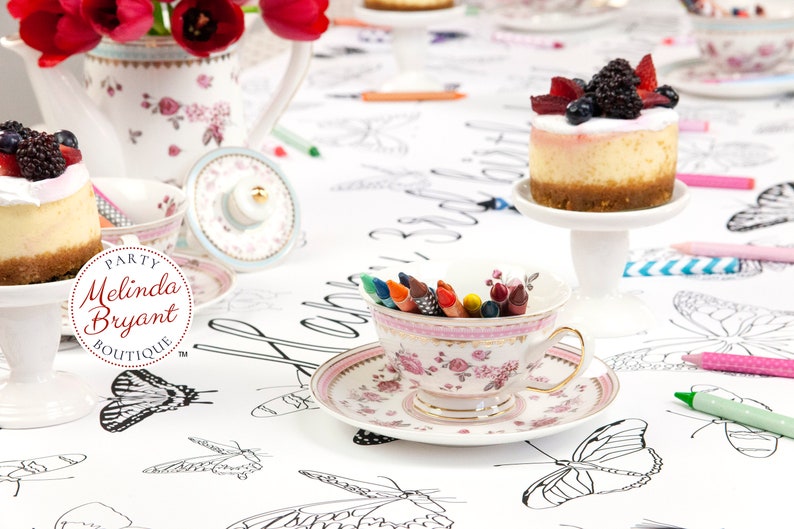 Berry covered mini cheesecakes and tiny cake stands, pretty teacups and saucers filled with crayons, and a china teapot filled with tulips are a fun way to stage this personalized butterfly coloring table runner.