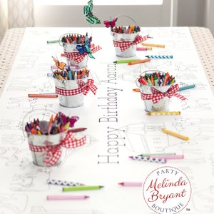 This table length view of my farm coloring table runner features horses, pigs, sheep, and a barn. The illustrated scene runs the length of the runner on both sides of the table. It is staged with miniature milk buckets filled with crayons.