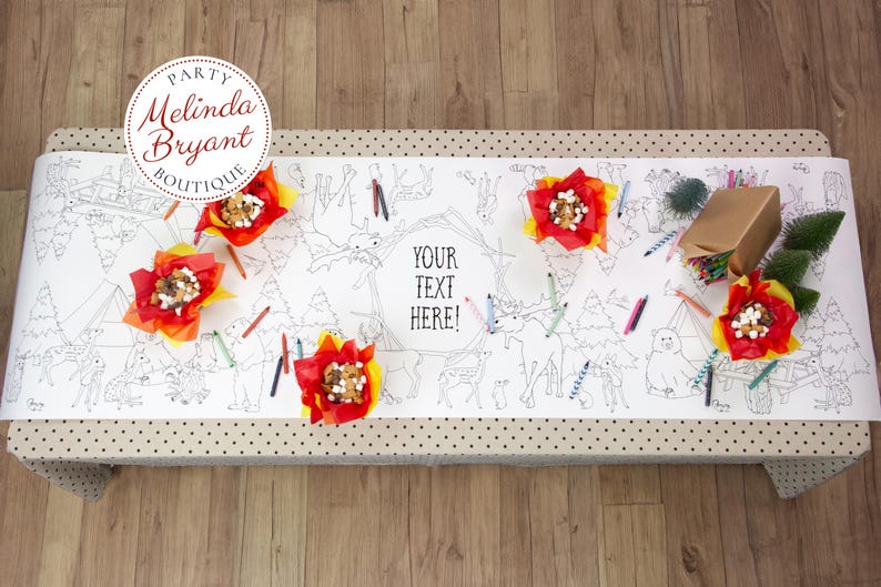 May include: A white coloring table runner with a black outline forest scene, featuring the text "YOUR TEXT HERE!". The runner is decorated with red and yellow flower-shaped treats, colored pencils, and a wrapped gift.