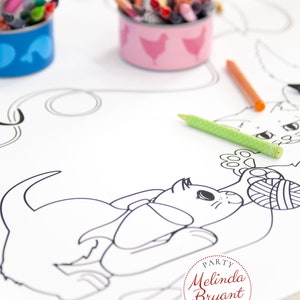 This image shows a closeup of a playful kitten with a ball of yarn. The kitten has a large bow around it's neck. In the background are repurposed tuna cans with cute chicken and tuna labels (free printables available on my website). The cans are filled with crayons.
