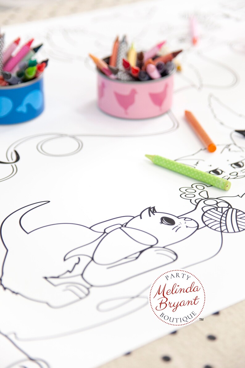 This image shows a closeup of a playful kitten with a ball of yarn. The kitten has a large bow around it's neck. In the background are repurposed tuna cans with cute chicken and tuna labels (free printables available on my website). The cans are filled with crayons.