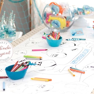 May include: A white table cloth with a shark-themed coloring page for kids. The table cloth has blue and white polka dots. There are several bowls of crayons in blue bowls on the table. The coloring page has the words "Happy Birthday" written on it.