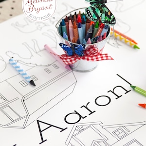 Detail showing the name Aaron, part of the custom text. Also shown: illustrations of two barns, horses, and pigs. A small milk pail filled with crayons sits on the table.