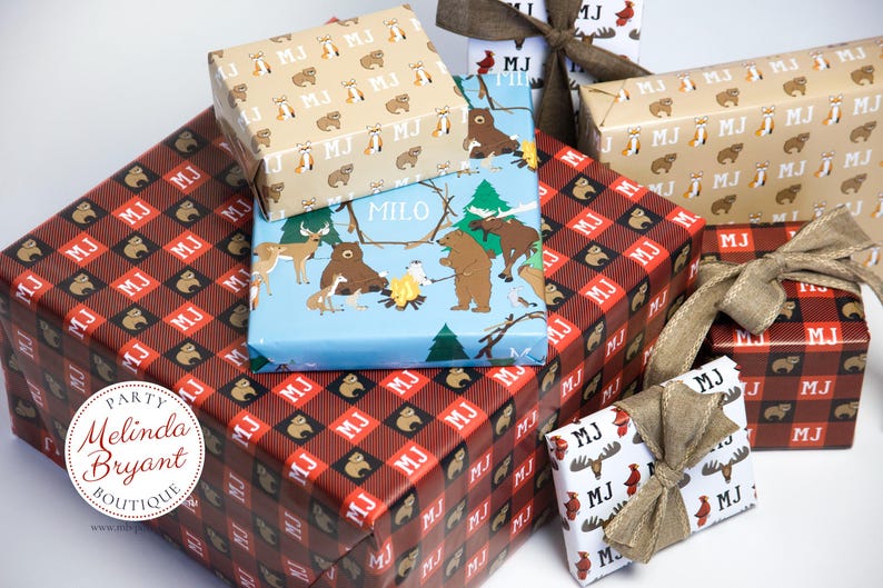 May include: Assortment of gift wrap featuring woodland animal designs. The wrapping paper is in a variety of colors and patterns, including red, blue, brown, and white. The wrapping paper is decorated with bears, deer, and other woodland animals. The wrapping paper is also decorated with the letters "MJ" and "MILO".
