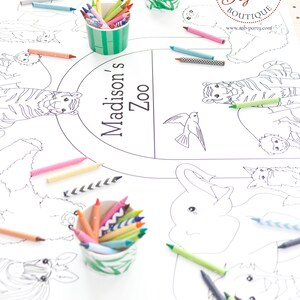 May include: A white paper coloring sheet with a zoo animal theme, featuring illustrations of tigers, elephants, and giraffes. Colorful crayons in various shades are scattered around the sheet and in decorative cups. The text "Madison's Zoo" is printed on the sheet.