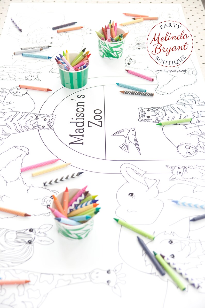 May include: A white paper coloring sheet with a zoo animal theme, featuring illustrations of tigers, elephants, and giraffes. Colorful crayons in various shades are scattered around the sheet and in decorative cups. The text "Madison's Zoo" is printed on the sheet.