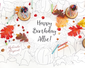 Puede incluir: Un mantel de mesa para colorear blanco con temática otoñal. El mantel presenta calabazas, hojas y las palabras "¡Feliz cumpleaños Allie!" El mantel está rodeado de decoraciones de otoño, incluyendo crayones, hojas y frascos de crayones. El mantel es de Melinda Bryant Boutique.