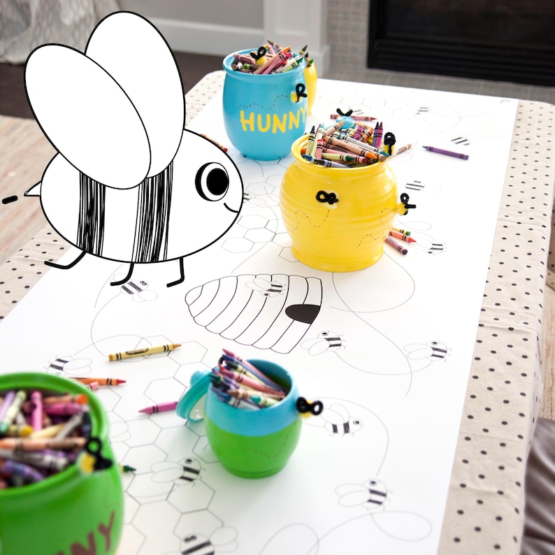 A table is set for a bee themed party or baby shower. A table length coloring page is laid over a dotted tablecloth. The design features happy bees, honeycombs, and a hive in the center. Optional text runs lengthwise along the edges. There are brightly painted honey jars filled with crayons on the table. This listing is for the coloring table runner only.