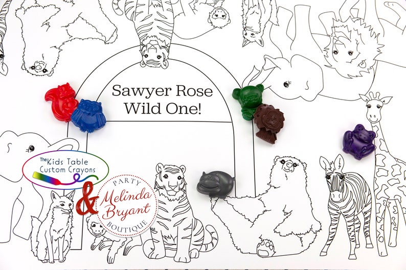 May include: A white coloring placemat with a black outline of various zoo animals, including a tiger, zebra, and giraffe. Colorful animal-shaped crayons in red, blue, green, brown, gray, and purple are scattered across the placemat. Text reads "Sawyer Rose Wild One!"