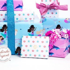 May include: A collection of gift boxes wrapped in mermaid-themed wrapping paper. The boxes are decorated with pink and blue ribbons, and the paper features images of mermaids, seashells, and stars. The text "Happy Birthday Sadie" is printed on the boxes.