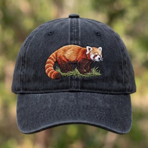 Può includere: Cappellino da baseball grigio scuro con un ricamo di un panda rosso. Il panda rosso è raffigurato in tonalità di rosso, marrone e bianco, su erba verde. Il cappellino ha una visiera curva e un classico design a sei pannelli.