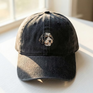 Pode incluir: Boné de beisebol de ganga preta com um retrato de cão bordado. O cão tem pelo castanho, preto e branco. O boné tem uma aba curva e um design clássico de seis painéis, adequado para uso casual.
