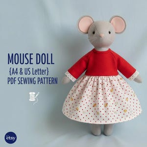 May include: A gray mouse doll wearing a red long-sleeved top and a white skirt with red polka dots and small bear illustrations. The doll has pink ears and is a PDF sewing pattern.
