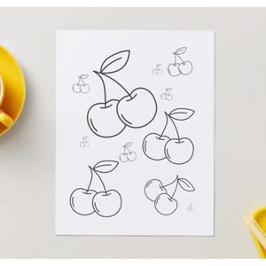 May include: A black and white line drawing of cherries on a white paper. The drawing features multiple clusters of cherries with stems and leaves. A yellow teacup and saucer are in the upper left corner, and a yellow dish is in the lower right corner.