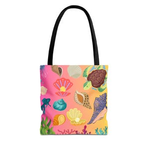 May include: Tote bag with a black handle and a colorful design featuring various seashells, a sea turtle, and coral. The background transitions from pink to yellow. The bag is designed for carrying items.