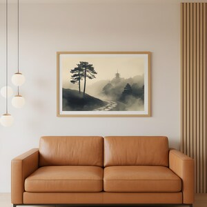 May include: A framed landscape print featuring a misty mountain scene with a winding path and a pagoda in the distance. Two tall trees stand on a hillside. The print is displayed above a brown leather sofa.