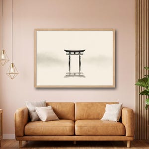 May include: A framed print featuring a minimalist Japanese Torii gate illustration in black ink. The artwork is set against a soft, neutral background, creating a serene and calming aesthetic. The print is displayed above a brown leather sofa.
