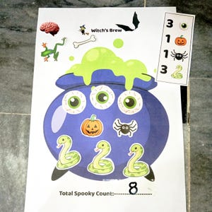 May include: A white activity sheet titled Witch's Brew featuring a large purple cauldron with green bubbling liquid. The cauldron is decorated with three eyeballs, a pumpkin, and three snakes. A side column lists numbers and icons, with the total count 8.