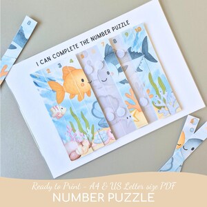 Peut inclure: Un puzzle de nombres sur le thème marin, avec des illustrations colorées de poissons et de coraux. Les pièces du puzzle sont numérotées de 2 à 10. Le texte "I CAN COMPLETE THE NUMBER PUZZLE" est visible.