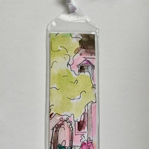 May include: A clear plastic bookmark with a watercolor illustration of a pink house with a green tree and flowers. The house has a door and a window.