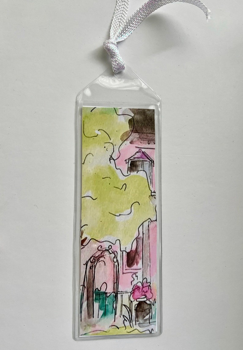 May include: A clear plastic bookmark with a watercolor illustration of a pink house with a green tree and flowers. The house has a door and a window.