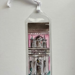 May include: A clear plastic bookmark with a watercolor illustration of a pink building with a sign that reads "The Olde Brick House Restaurant & Tavern".