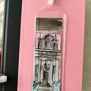 May include: A pink and white illustrated bookmark featuring a building with the text "The Olde Pink House Restaurant & Tavern".