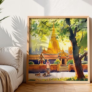 Puede incluir: Pintura a la acuarela de un templo dorado con una alta aguja, enmarcada en madera clara. Una persona pasea a dos perros por un camino frente al templo. La obra de arte está situada sobre un fondo de follaje verde y cielo brillante.
