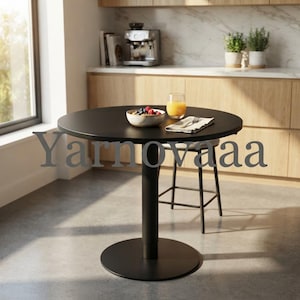 May include: A round black pedestal table with a central column base. On the tabletop sits a ceramic bowl filled with mixed berries and granola, a glass of orange juice, and a folded white napkin. The word Yarnovaaa is overlaid on the image.