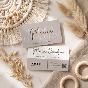 Pode incluir: Dois cartões de visita retangulares com o nome Monica Davidson, o título Owner | Designer, ícones de redes sociais, detalhes de contato e um código QR. Um cartão tem fundo cinza claro, o outro é branco com uma seção inferior cinza.