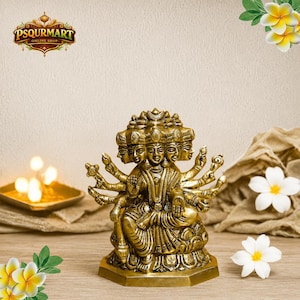May include: A metallic gold-colored statue of a deity with multiple faces and many arms, seated in a cross-legged position on a lotus-shaped base. The figure features intricate carvings and is displayed with a logo reading PSQURMART ONLINE SHOP.